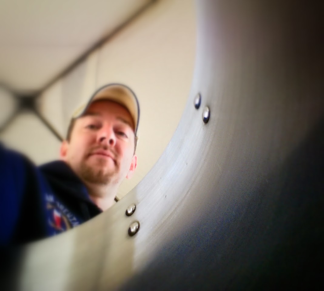 Brian Benham peering into a stainless steel brew kettle while shooting brewery content